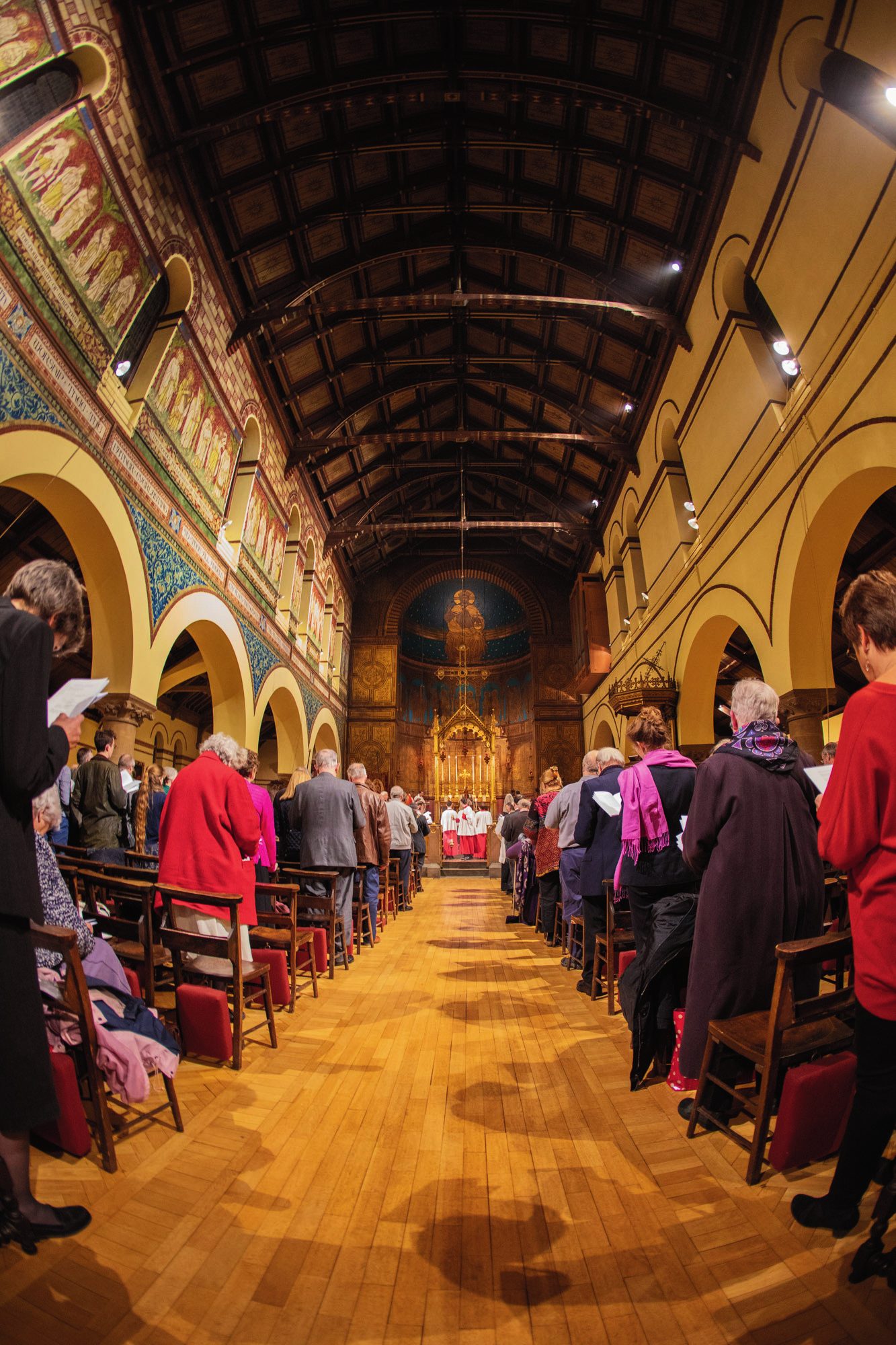 The nave of St Barnabas looking east towards the altar, the congregation standing as the procession approaches.